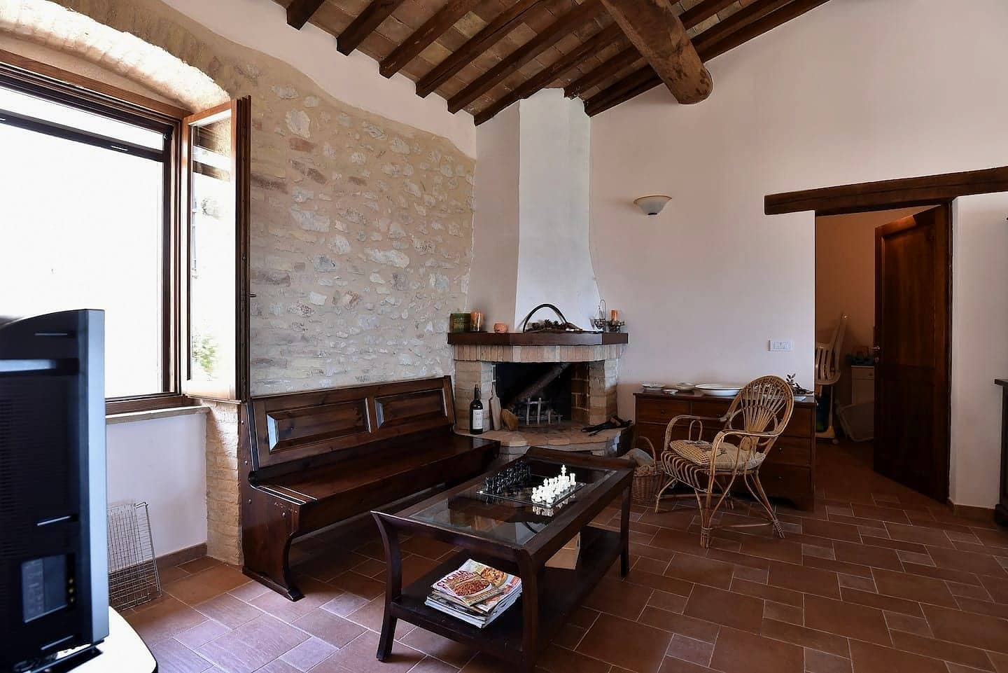 Il salotto con il caminetto ad angolo, la parete in pietra a vista e la panca in legno