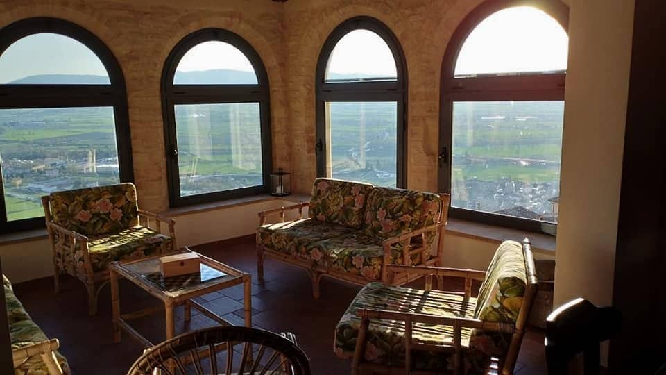 La loggia nella luce bassa del sole, con i divanetti a fiori sotto gli archi